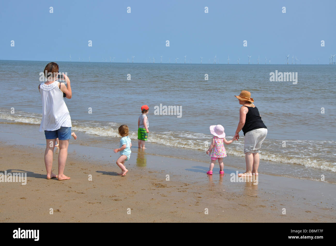 woman taking photo of family on beach, Skegness, Lincolnshire, England, UK Stock Photo