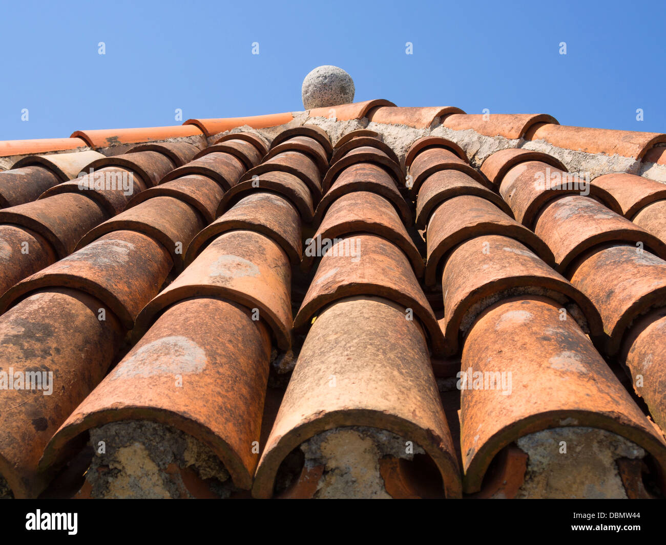 fragment of ancient tile roof with stone ball decoration on top Stock Photo