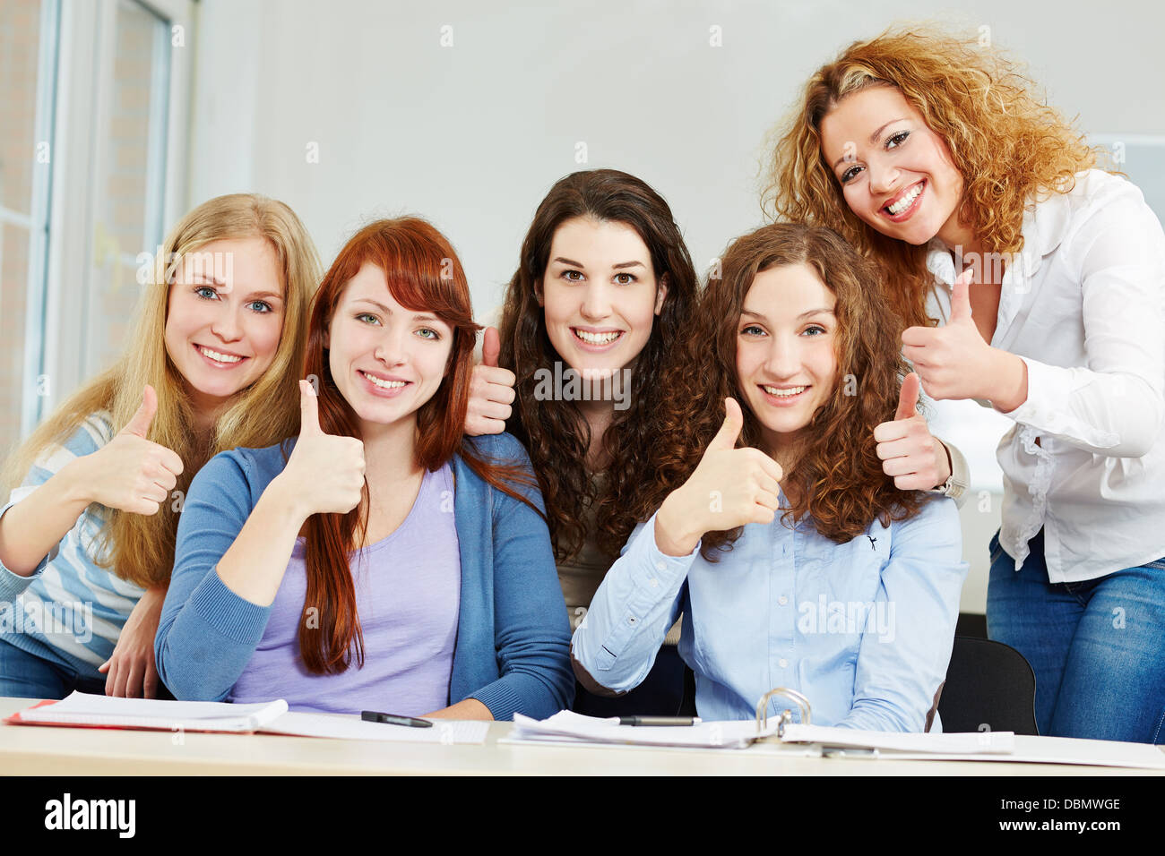 Happy successful women holding thumbs up in a university class Stock Photo