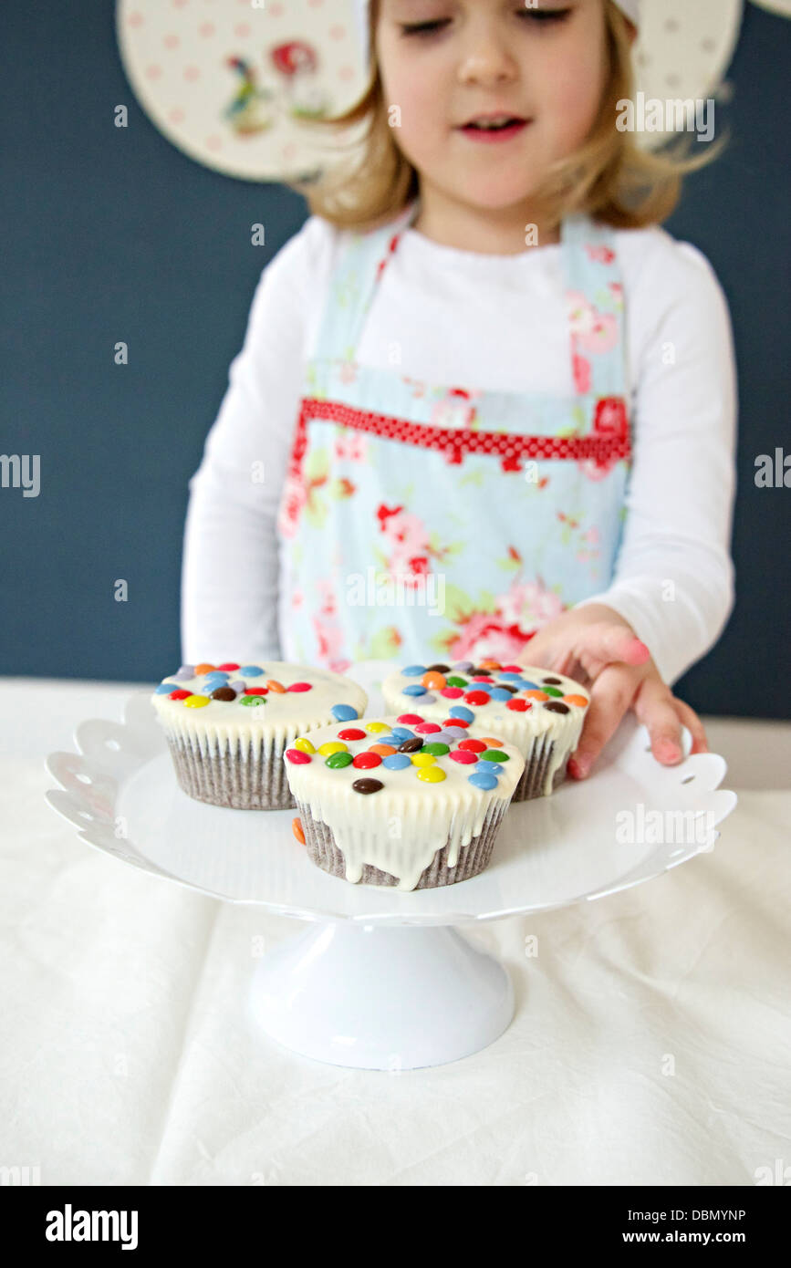 Little girl with chef's hat presenting muffins, Munich, Bavaria