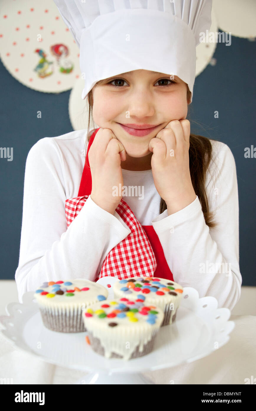 Little girl with chef's hat presenting muffins, Munich, Bavaria