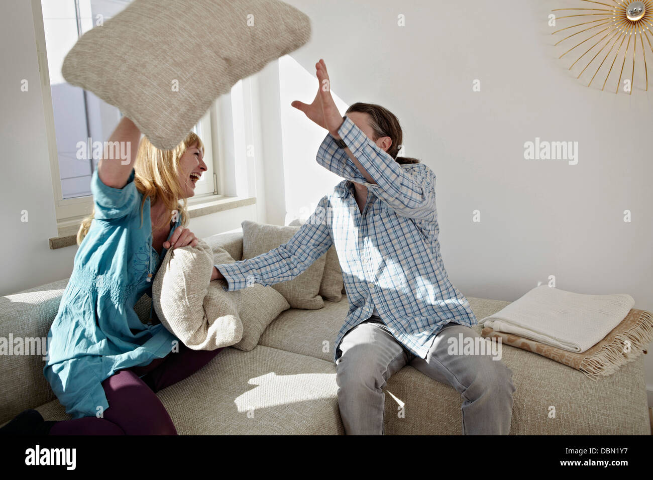 A Couple Pillow Fights In Their Living Room Stock Photo
