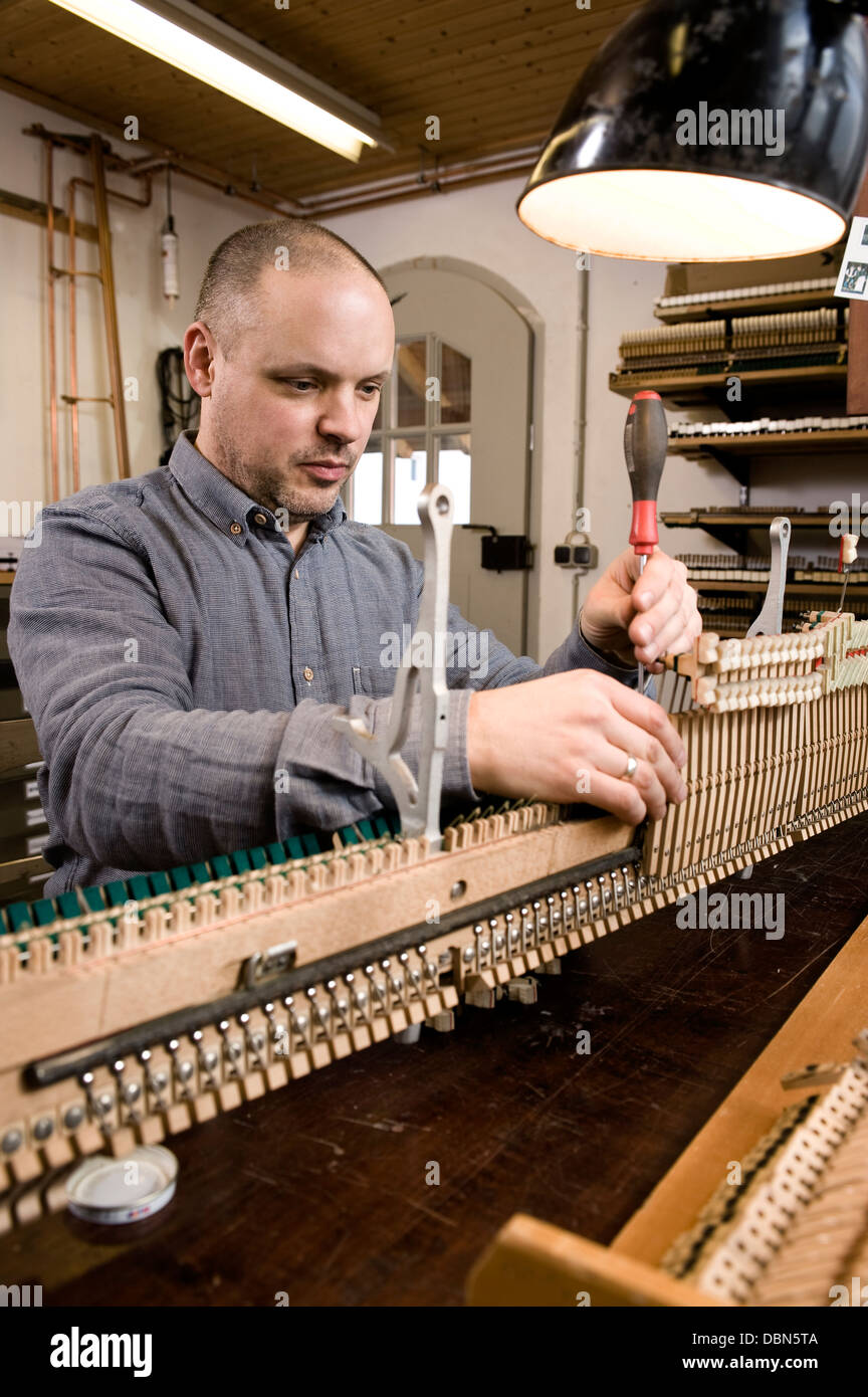Instrument maker adjusting musical mechanism of a piano, Regensburg, Bavaria, Germany Stock Photo