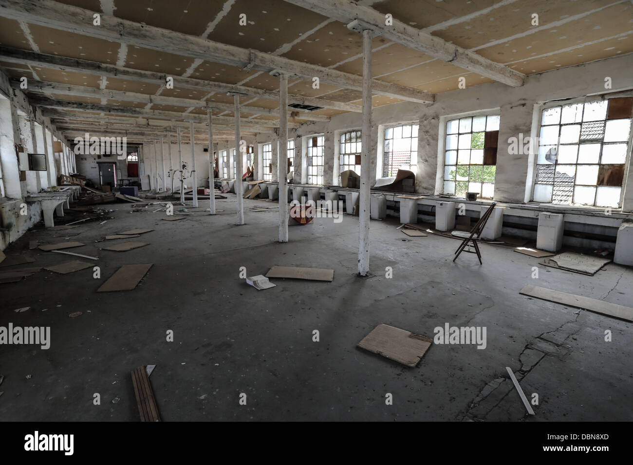 Abandoned factory with broken stuffs on the ground like chairs and wood panels. nobody. Interior Stock Photo