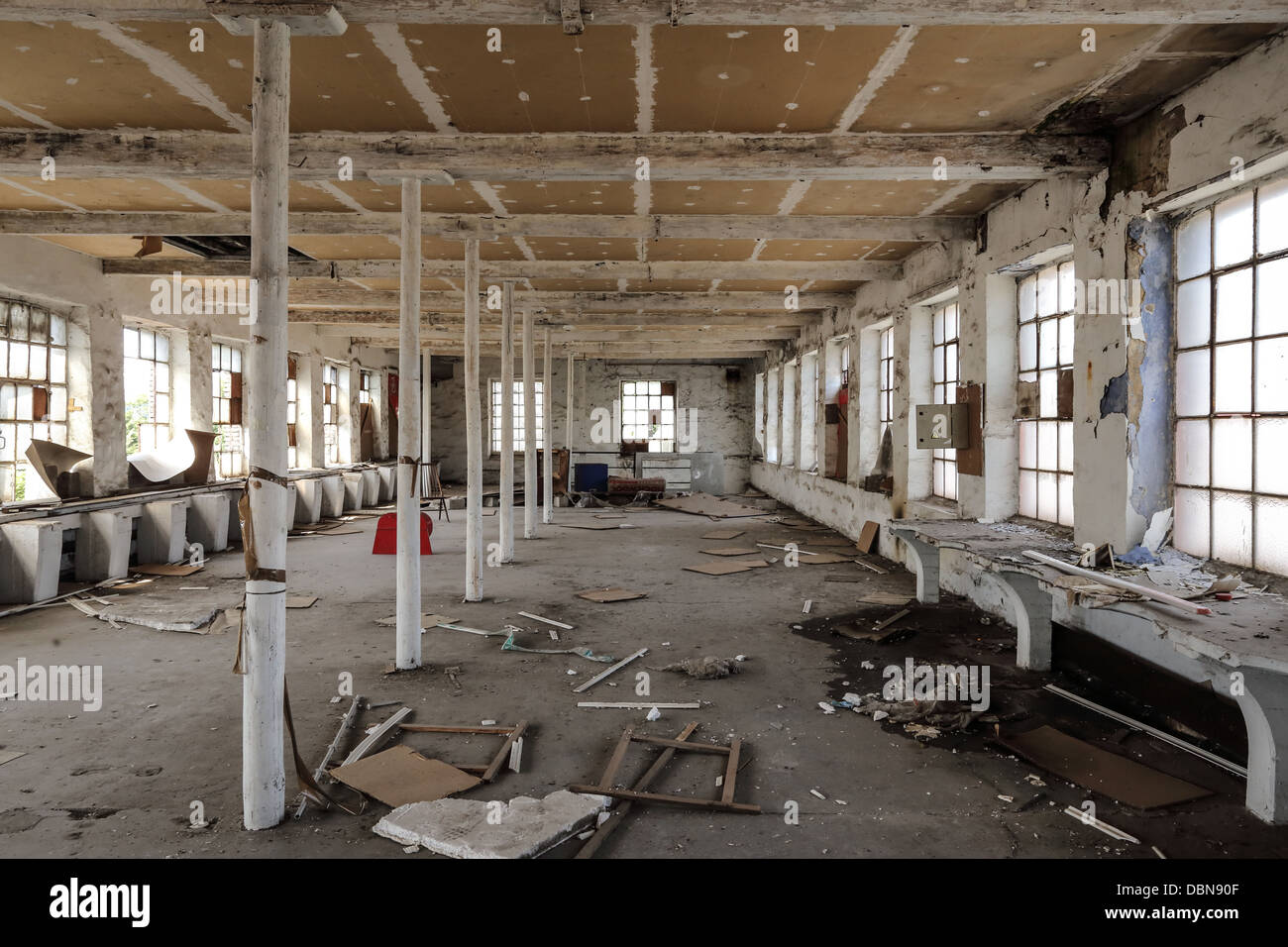 Abandoned factory with broken stuffs on the ground like chairs and wood panels. nobody. Interior Stock Photo