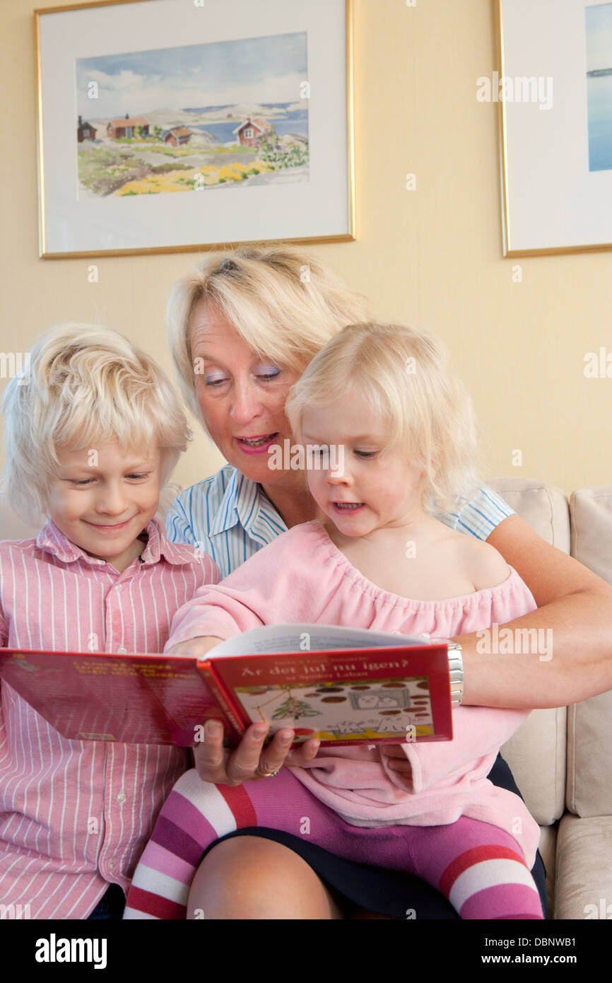 Children (4-5, 6-7) reading book with grandmother Stock Photo