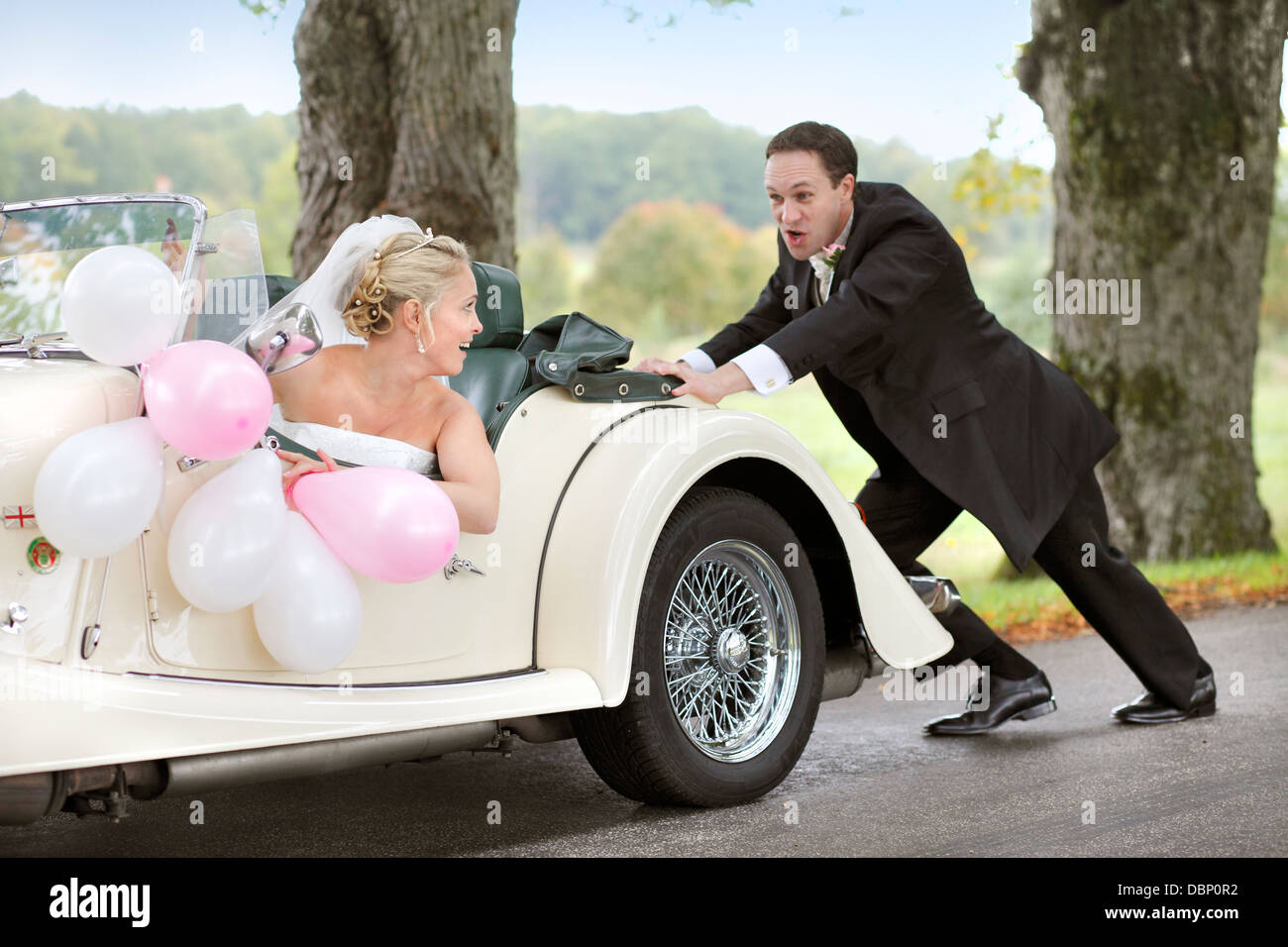 Groom pushing car with bride sitting inside Stock Photo Alamy