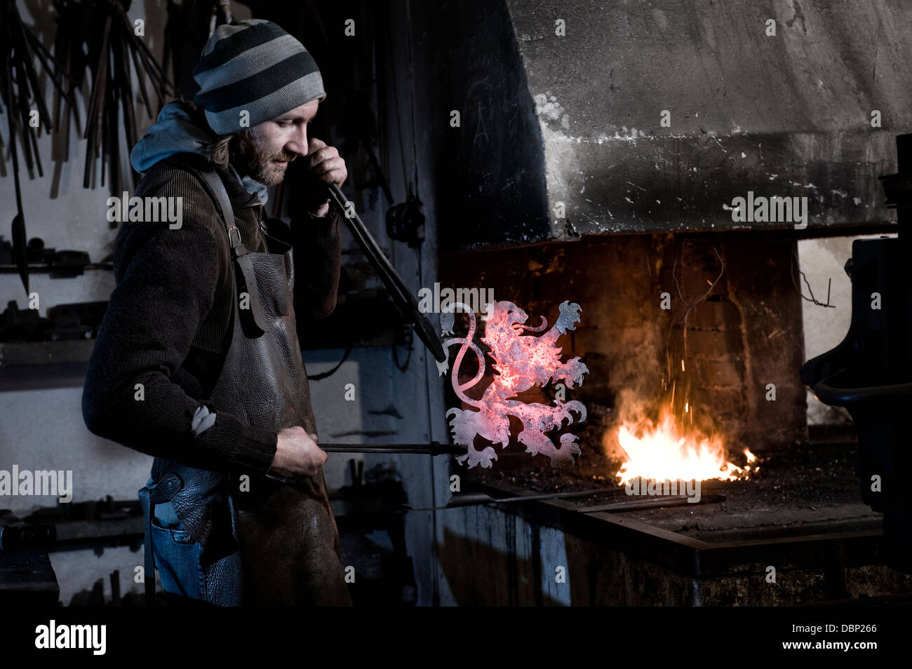 Blacksmith making coat of arms from iron, forge in background, Landshut, Bavaria, Germany Stock Photo