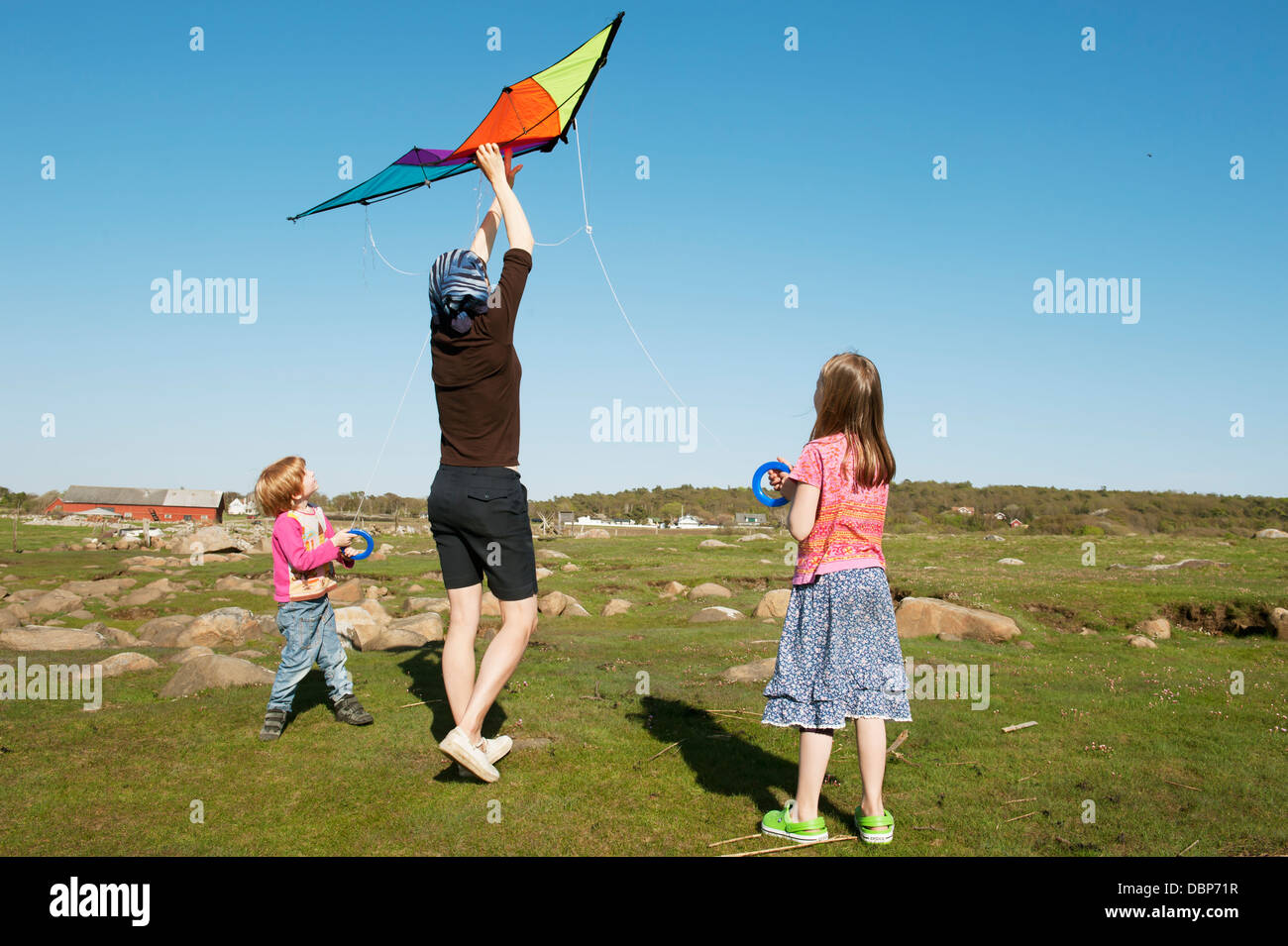 Mother flying kite with her kids (4-5), (8-9) Stock Photo