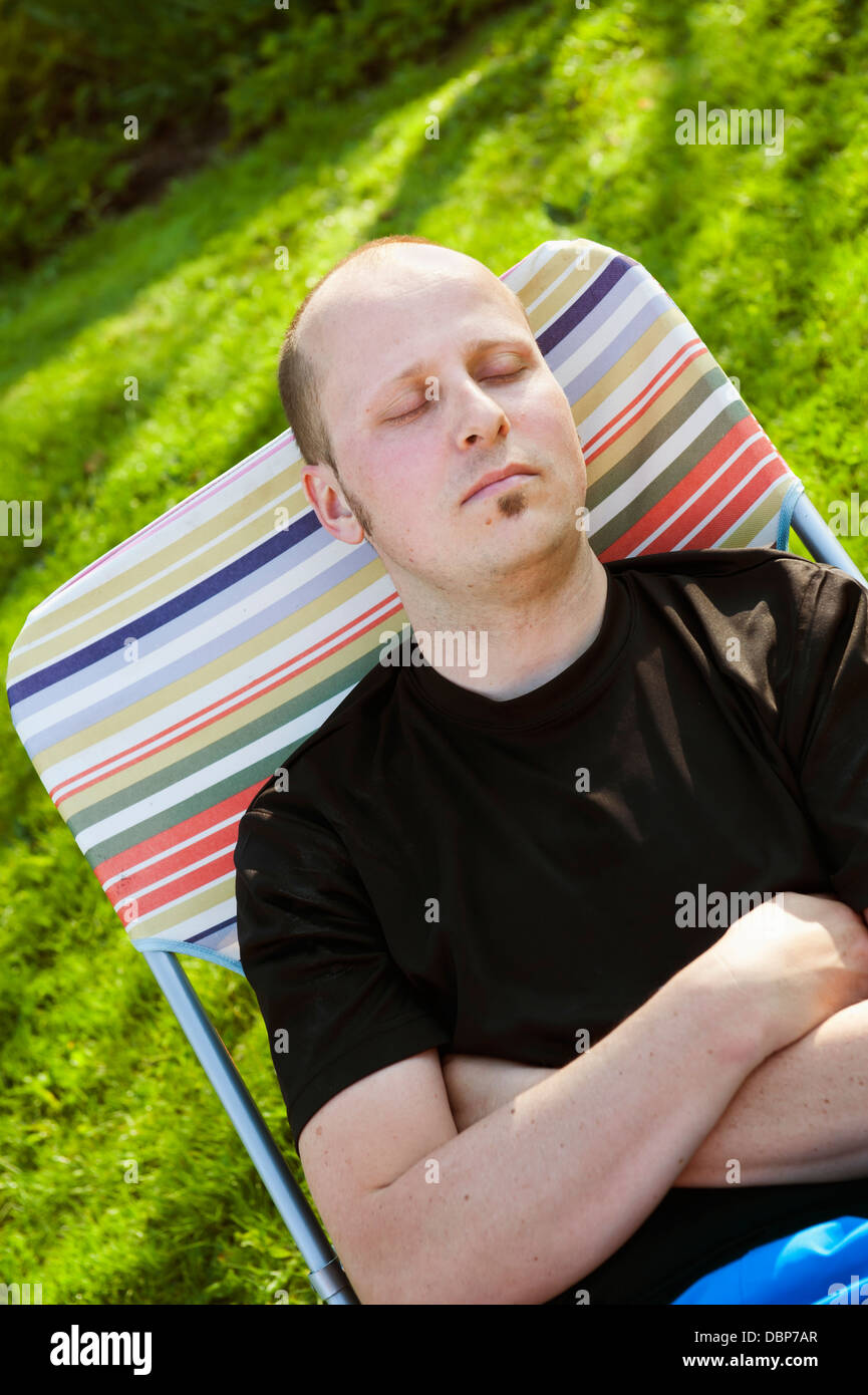 Portrait of man taking nap in deck chair Stock Photo - Alamy