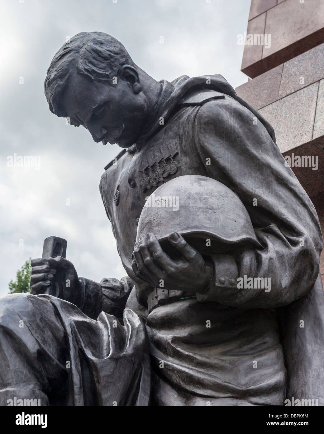 Soldier with bowed head holding helmet and gun at the Soviet War memorial for 5000 soldiers who died in WW2, Treptow, Berlin Stock Photo