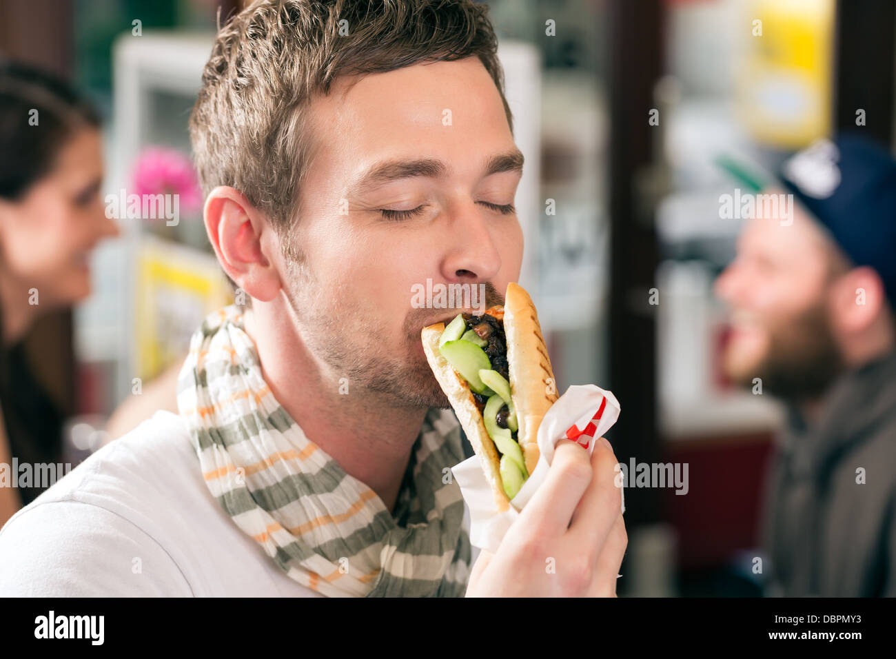 Hotdog - young customer in a snack bar eating delicious fast food ...