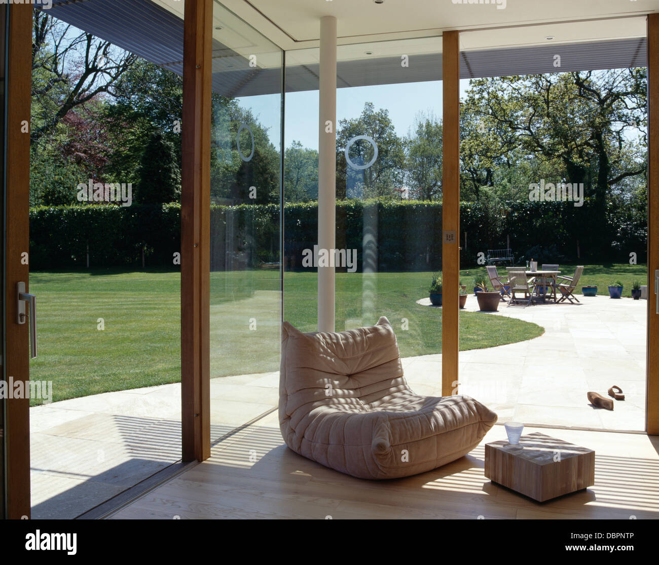 Cream Upholstered Chair In Corner Of Modern Glass Walled