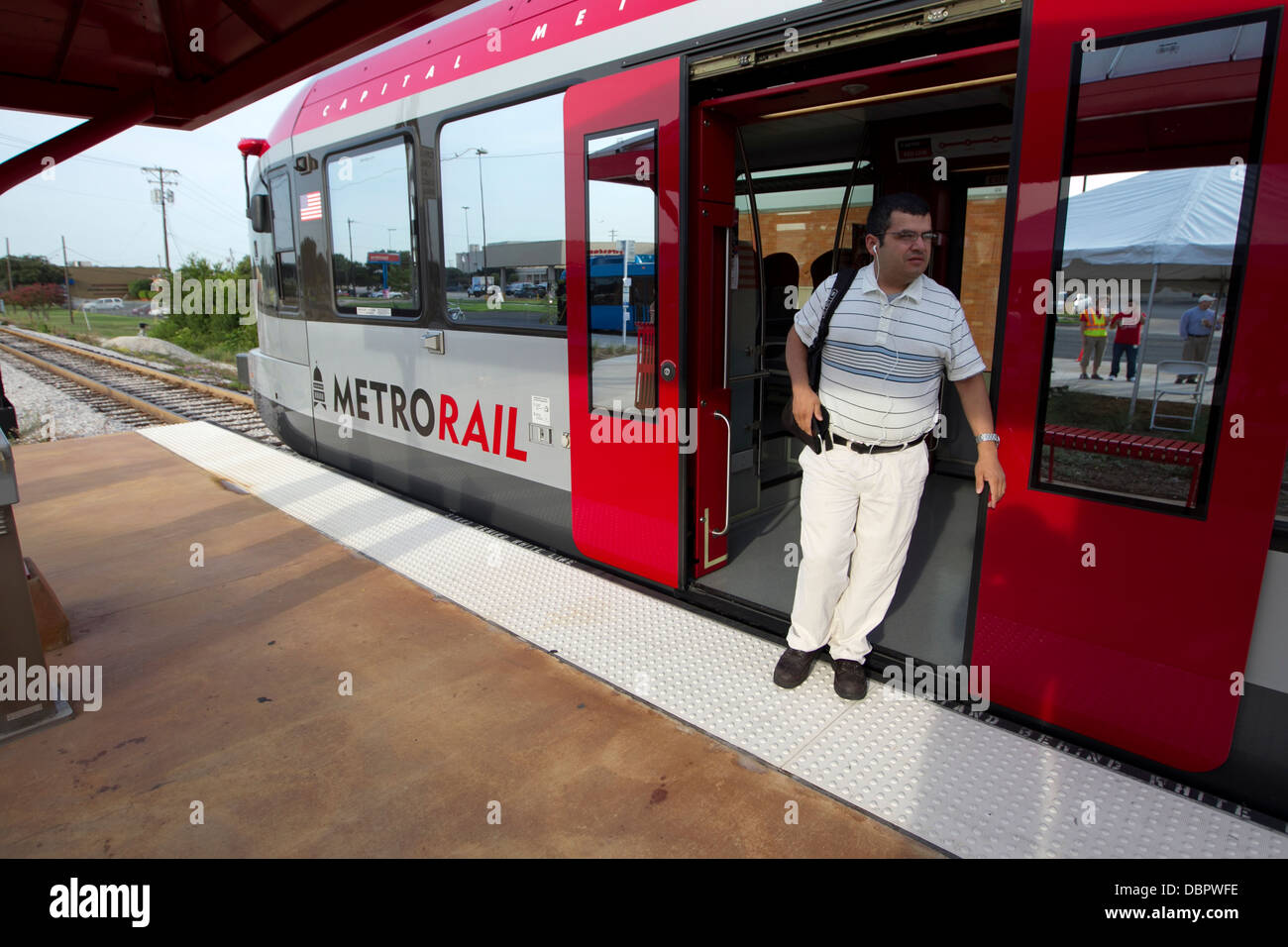 Morning commuter steps off of Metro-Rail train at one of the public transportation stops in Austin, Texas Stock Photo