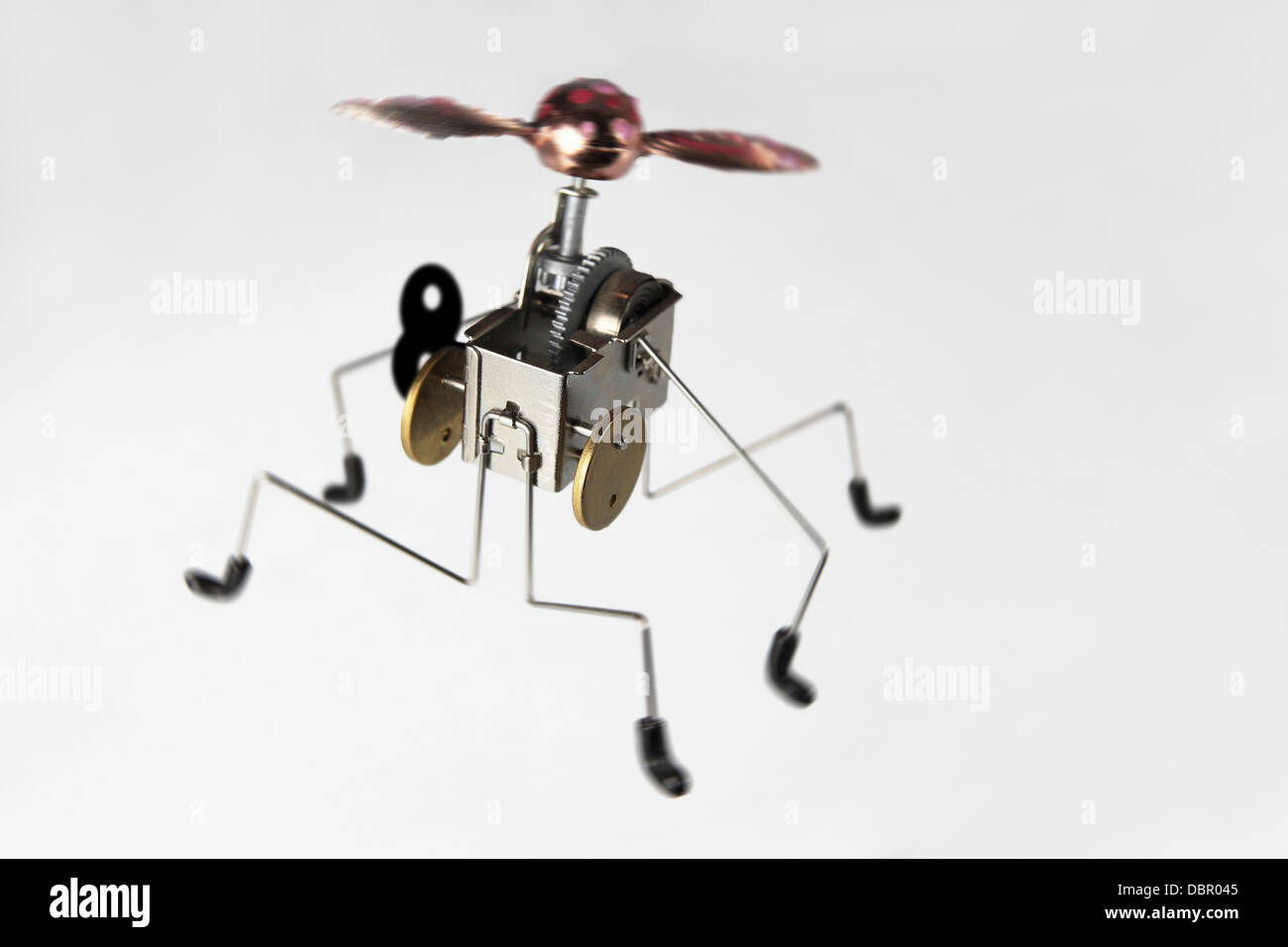 a strange metal sculpture, an alien cricket, jumpy spring mechanic with propeller...on a light surface. Stock Photo