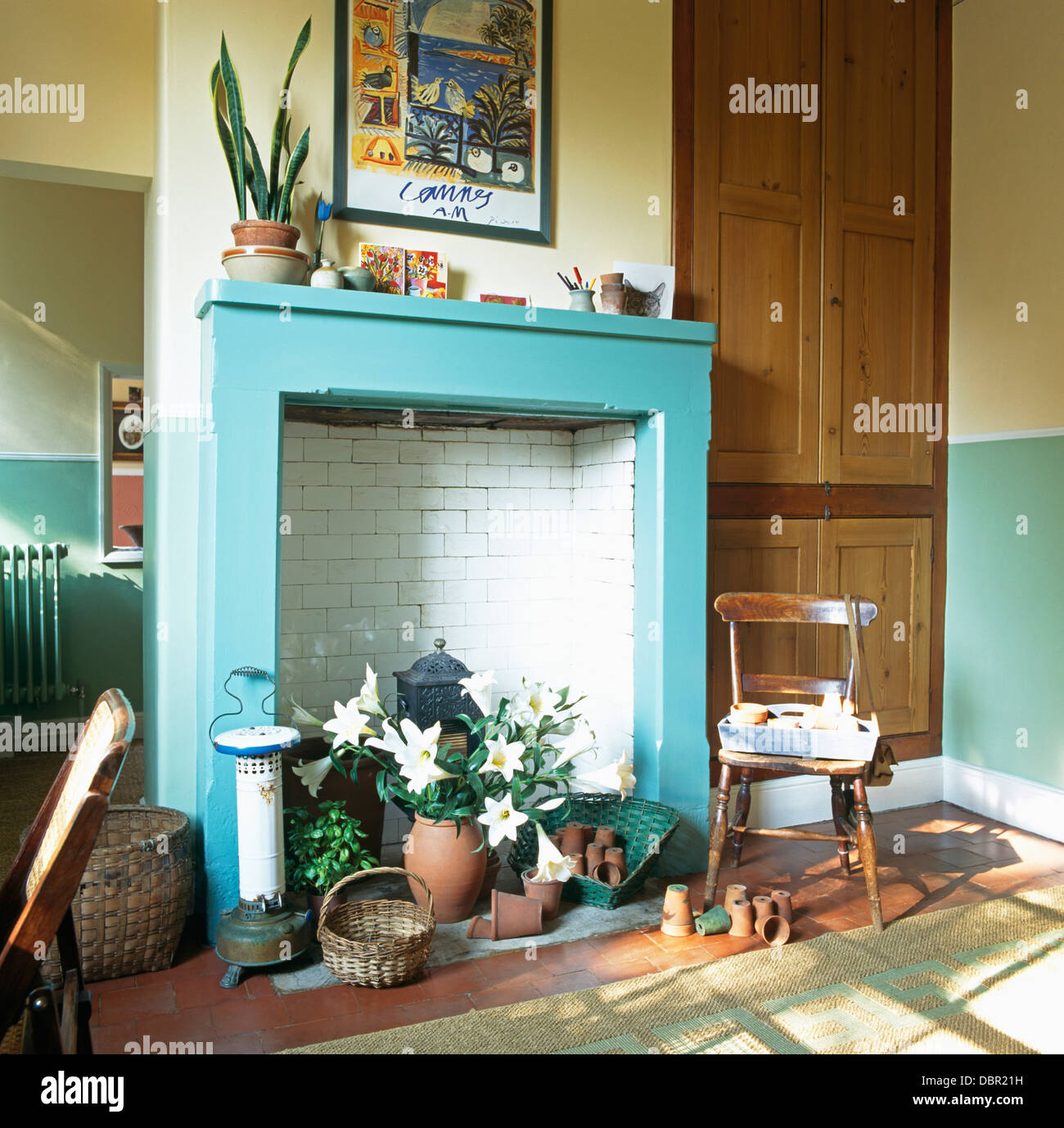 Old oil stove and wooden chair beside turquoise fireplace in economystyle dining room Stock