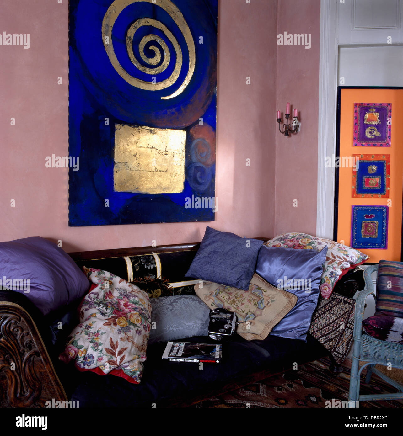 Gold and bright blue abstract painting above sofa piled with cushions