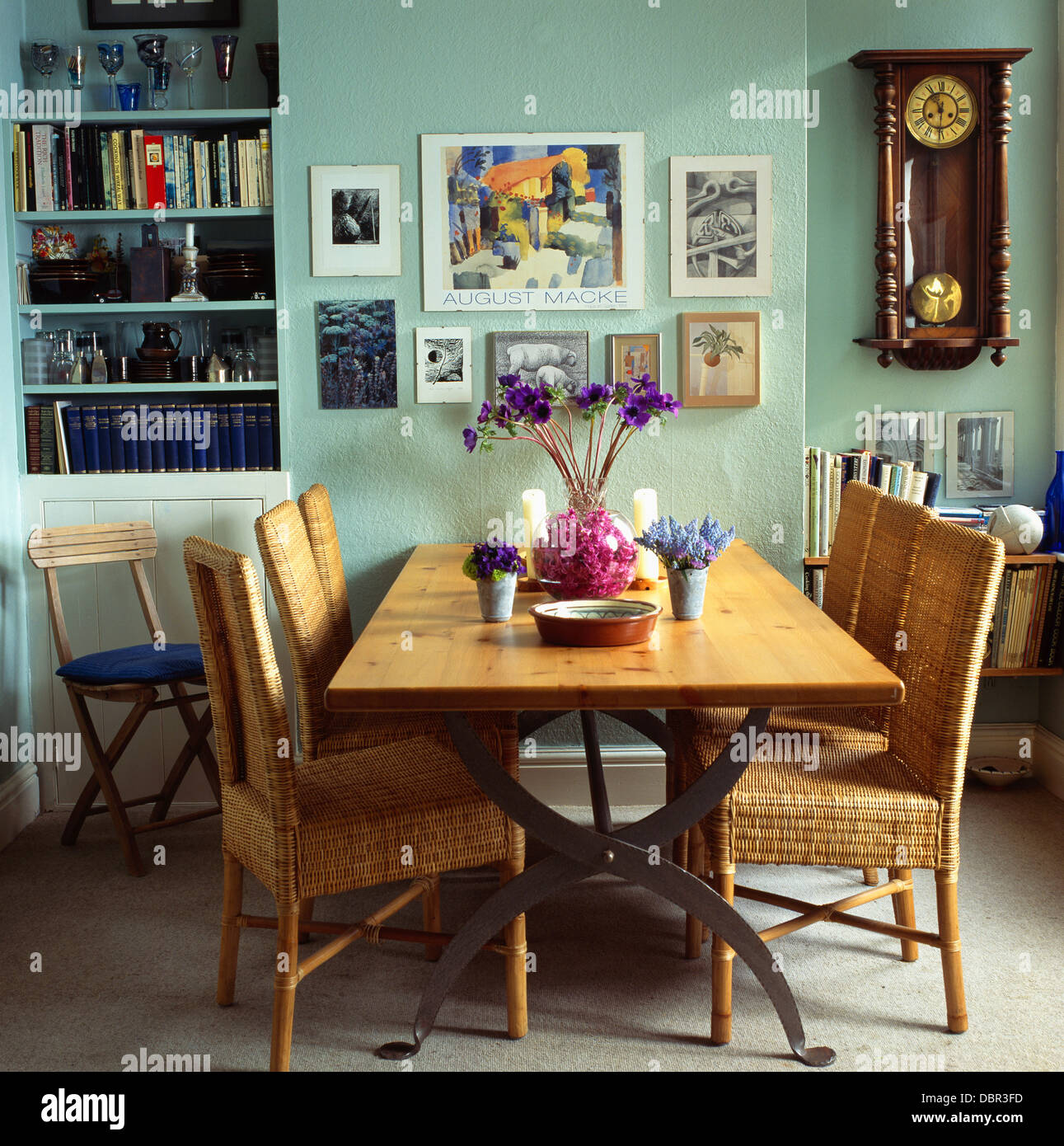 Group of pictures and antique wall clock in pale green dining room with