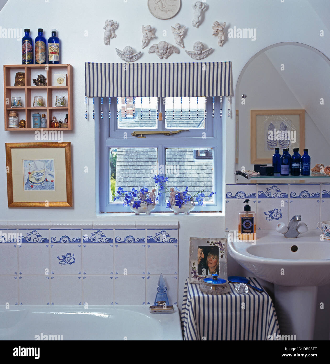 Striped blind on small window in cottage bathroom with blue+white