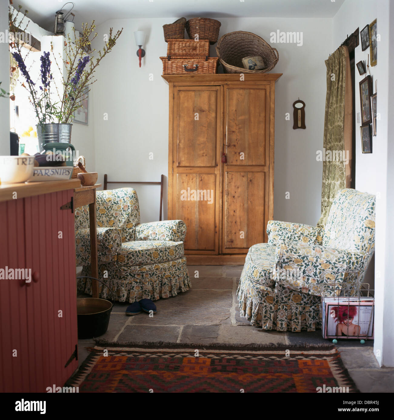 Baskets on top of antique pine cupboard in cottage kitchen with floral
