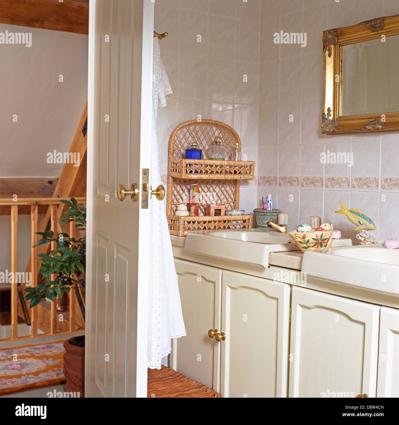 Wicker shelf unit on wall beside vanity unit with double basins in ...