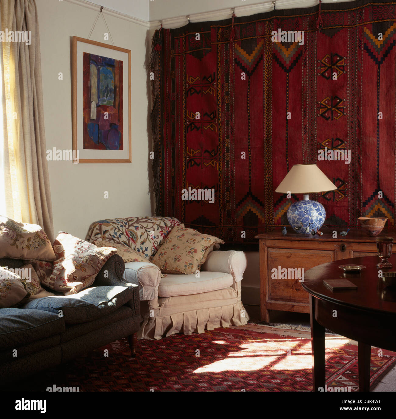 Old red Persian carpet hanging on wall in townhouse living room with