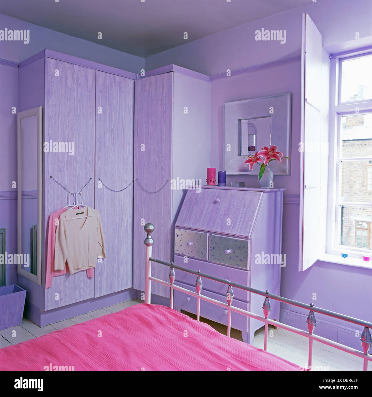 Pink bed cover on wrought iron bed in mauve economystyle bedroom with