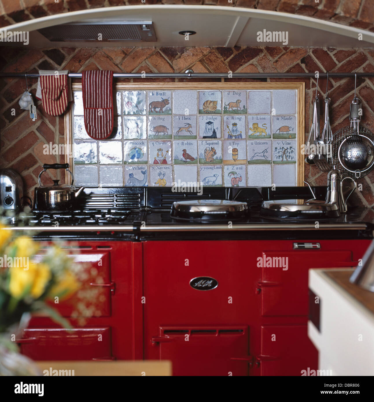 Close-up of pictorial wall tiles above red double Aga in country kitchen Stock Photo