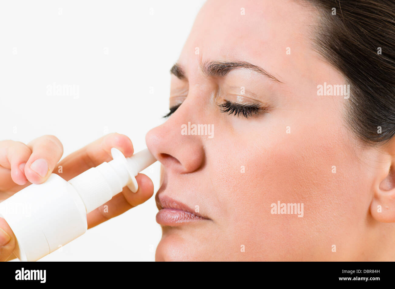 A young woman using nasal spray Stock Photo