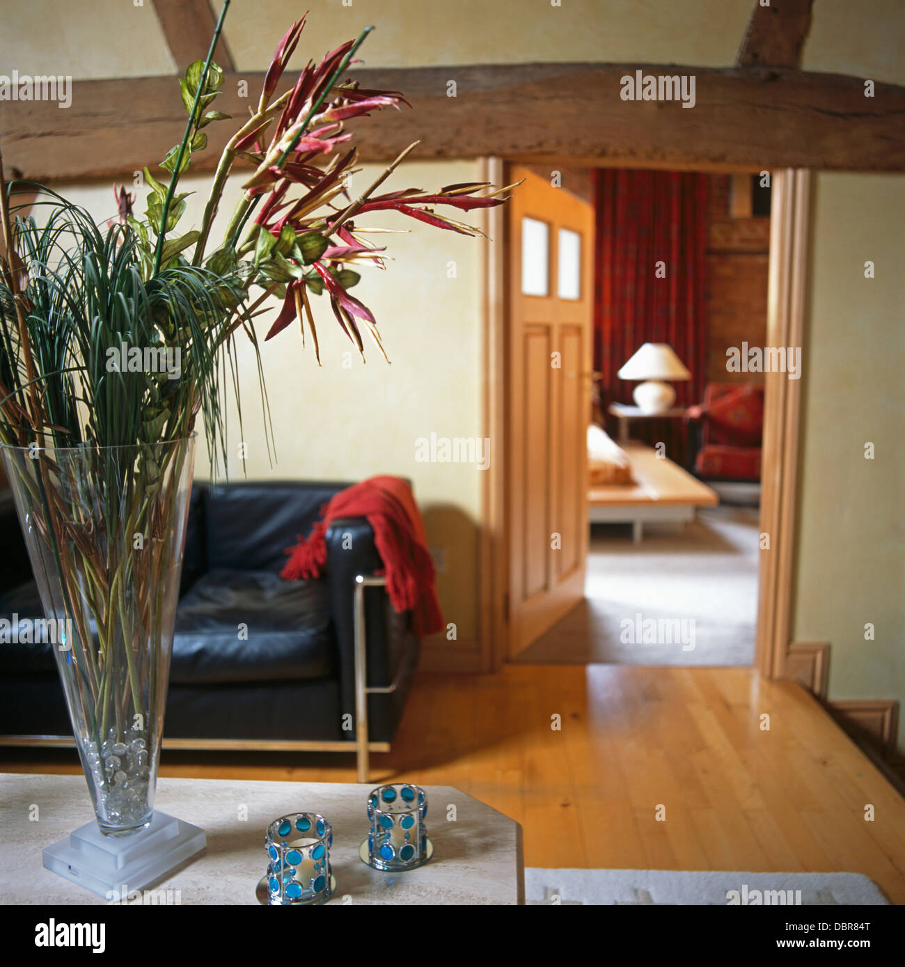 Flowers In Tall Glass Vase On Table With Beaded Candle Holders In