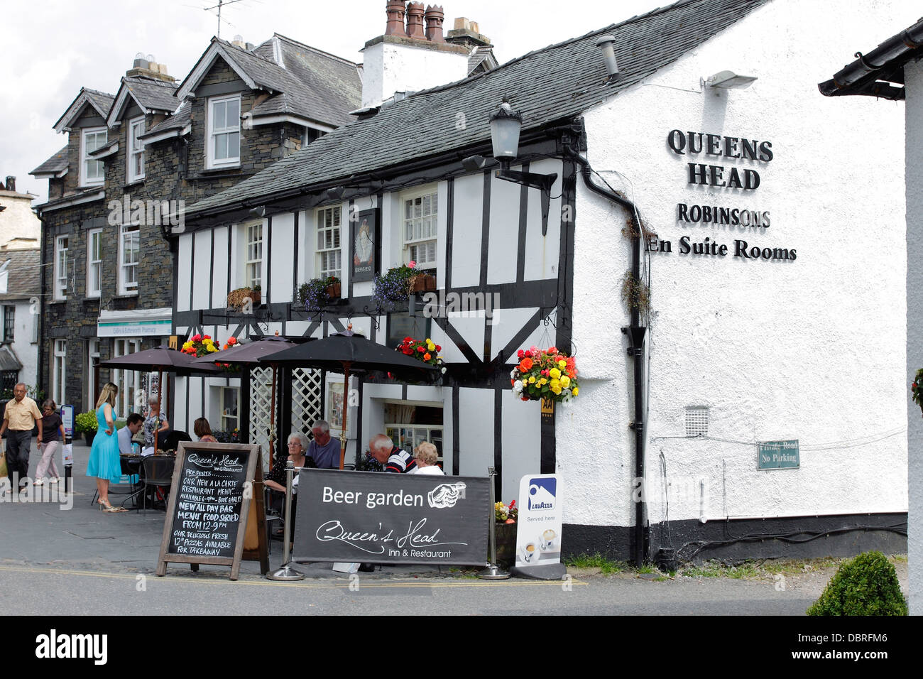 Customers eating and drinking outside the Queens Head Pub in the pretty Lakeland town of Hawkshead in Cumbria. Stock Photo