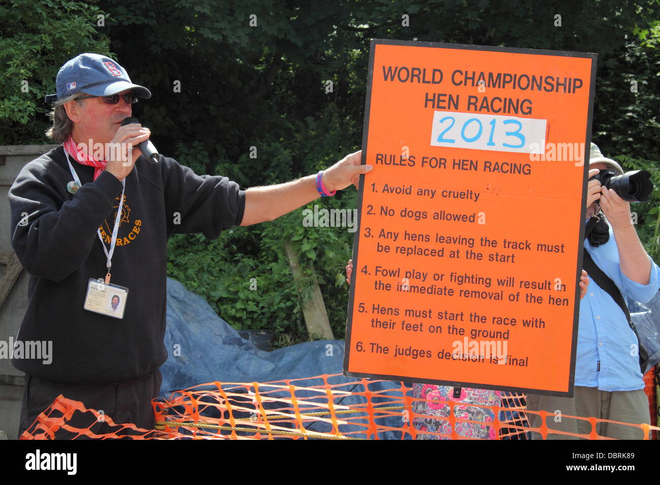 Bonsall, Derbyshire, UK. 3 August 2013. The Hen Racing World Championships take plaace in Bonsall. A race official outlines World Championship Hen Racing rules including  'no fowl play'.  Once underway, entrants are not allowed to touch their hens but some opt to coax them to the finish line by clucking.  Among the more colourfully named 2013 entrants was Hendo Nagasaki named after the 1970’s masked British wrestler. Credit:  Deborah Vernon/Alamy Live News Stock Photo