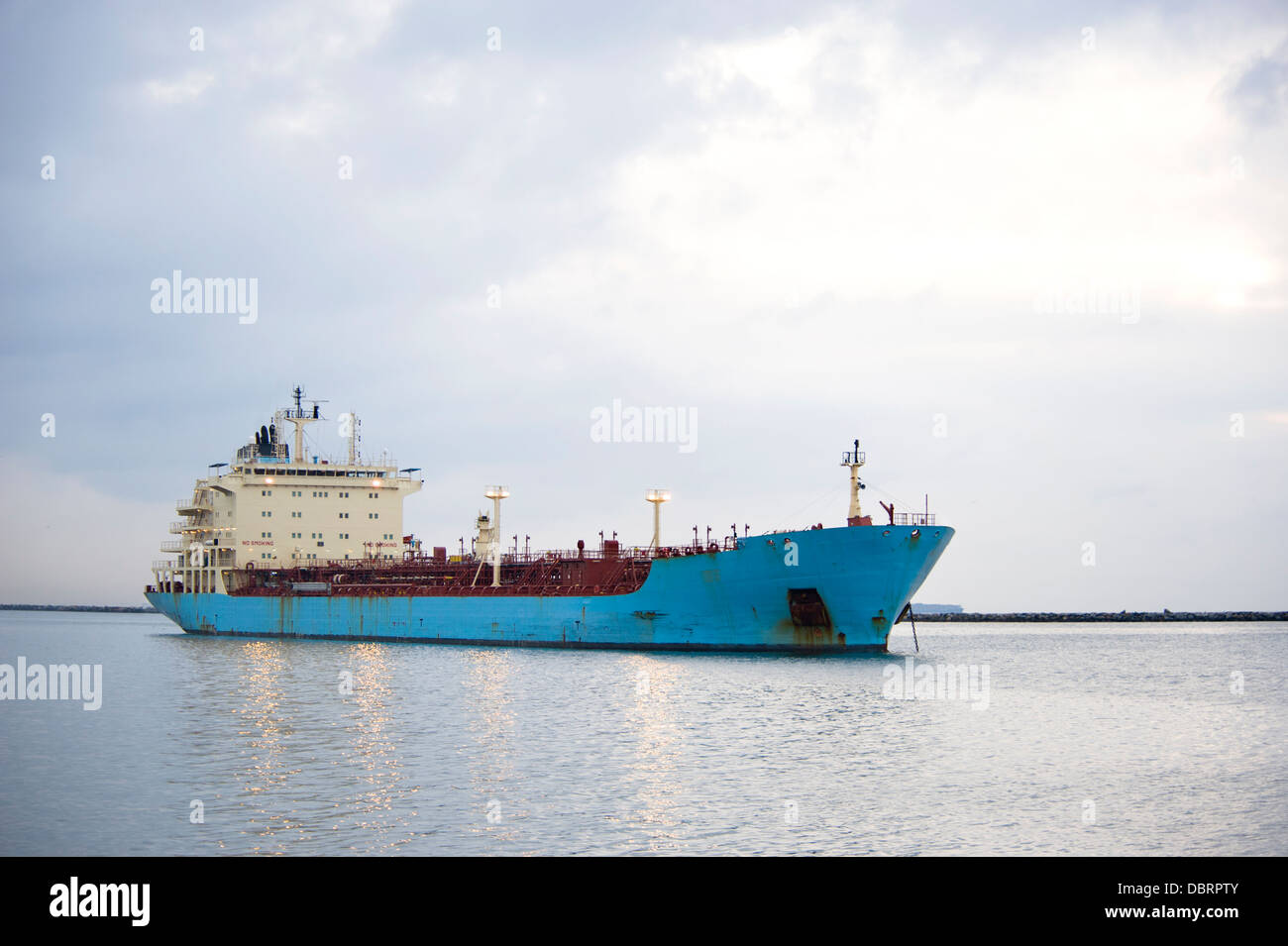 A blue shipping transportation freighter anchored just inside a port of call. Stock Photo