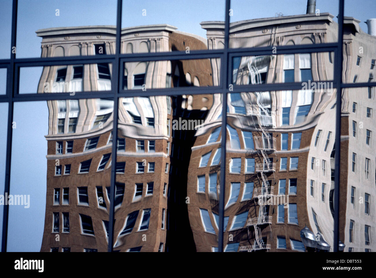 Two old brick buildings in downtown Long Beach, California, are reflected in the wavy glass windows of a modern office tower. Stock Photo