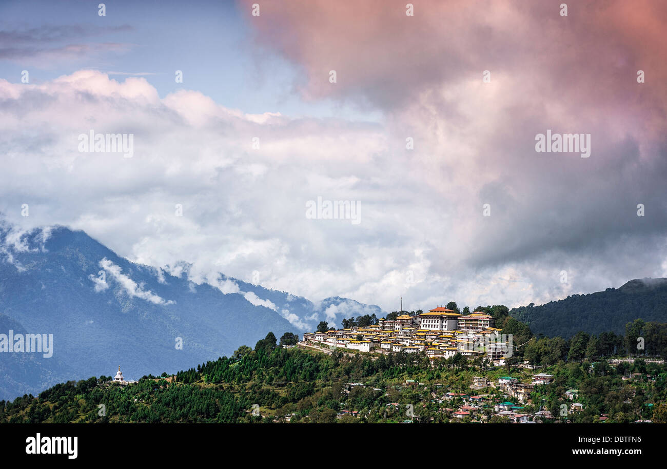 Ancient Buddhist monastery perched on top of high mountain top surrounded by other mountains shrouded in cloud on a fine day. Stock Photo