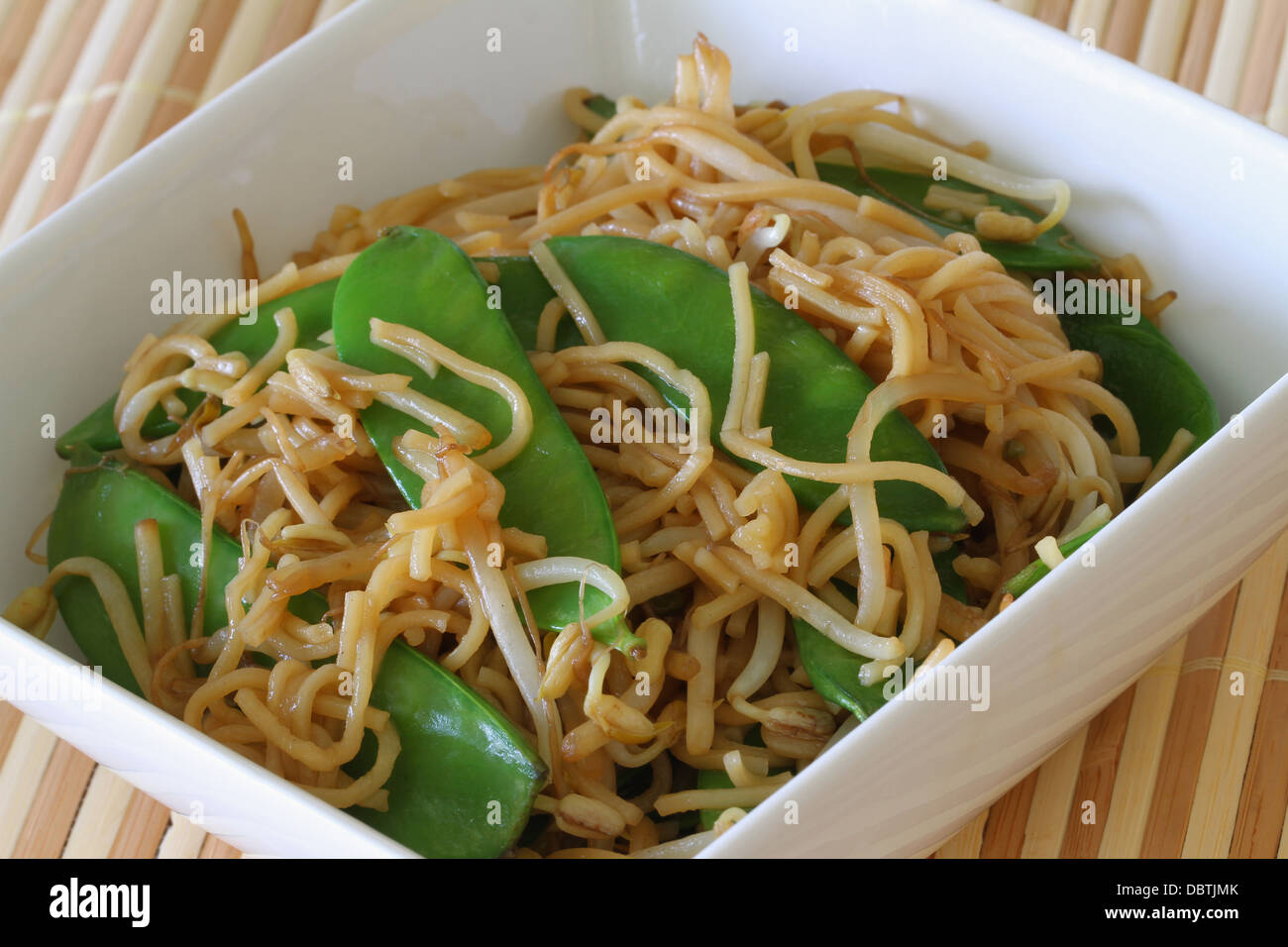 Bowl of egg noodles stir fried with snow peas and beansprouts Stock Photo