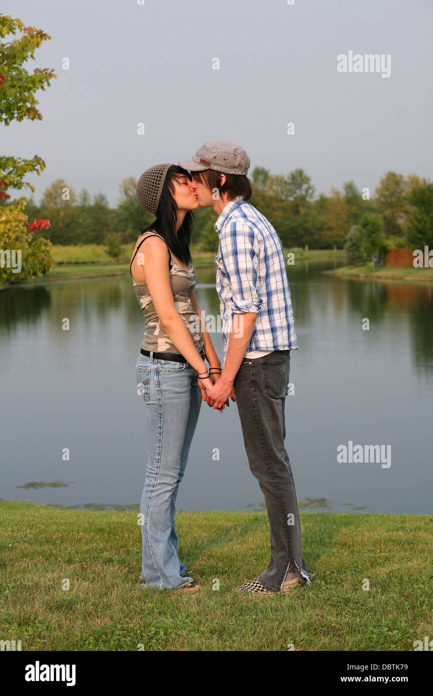trendy teen boy and girl kissing by a lake Stock Photo