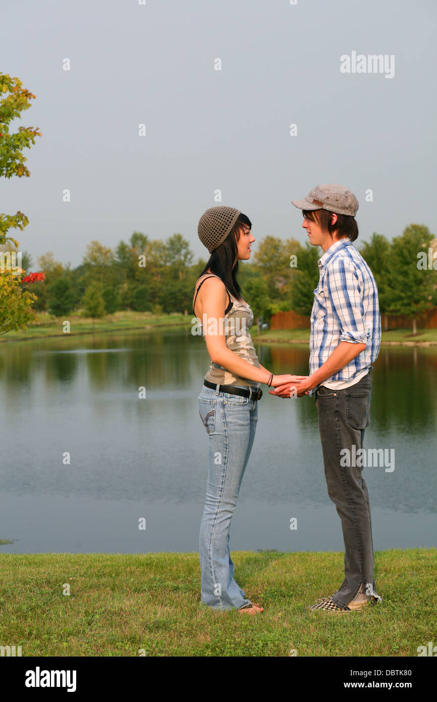 attractive teen boy and girl holding hands by a lake Stock Photo - Alamy