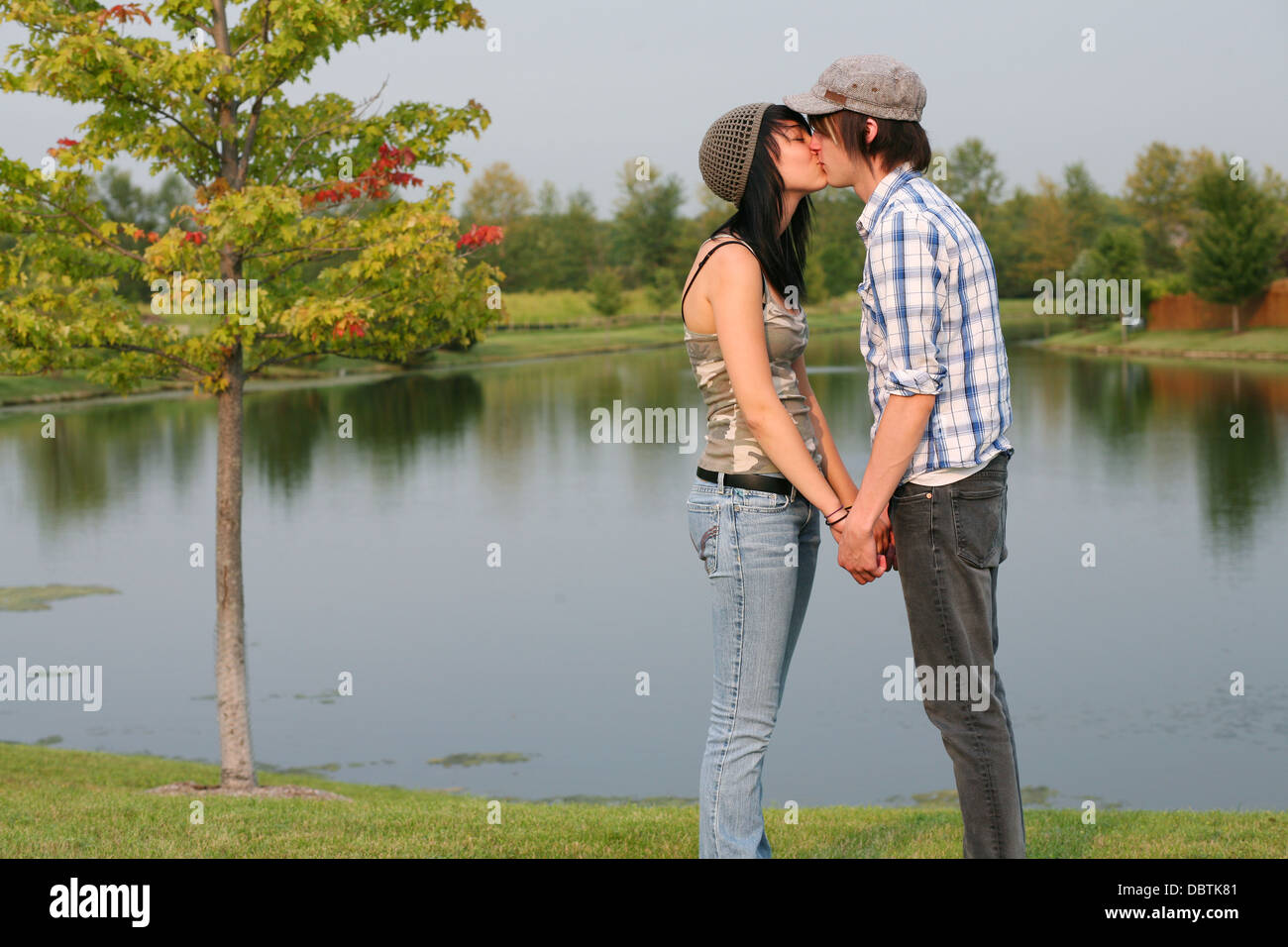 cute teen guy and girl kissing by a lake Stock Photo