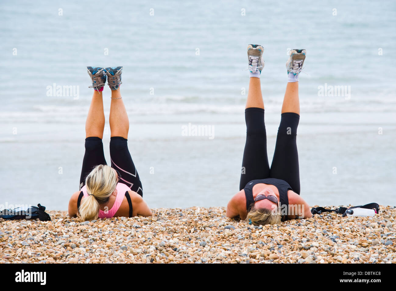 Two mature women having an early morning fitness workout on the beach at Brighton East Sussex England UK Stock Photo