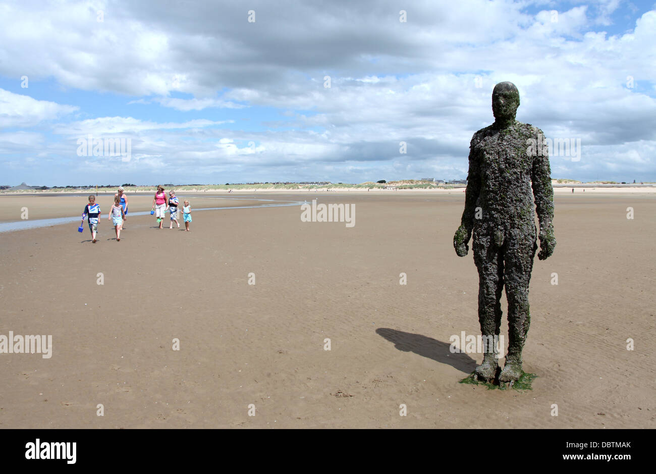 Family Walking on Crosby Beach to see one the iron men statues of