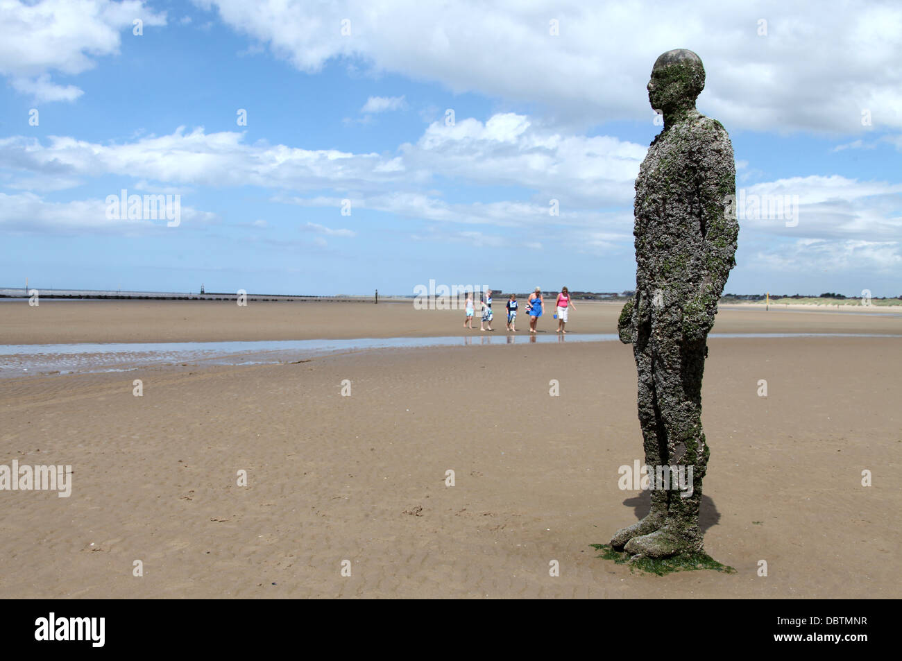 Family Walking on Crosby Beach to see one the iron men statues of