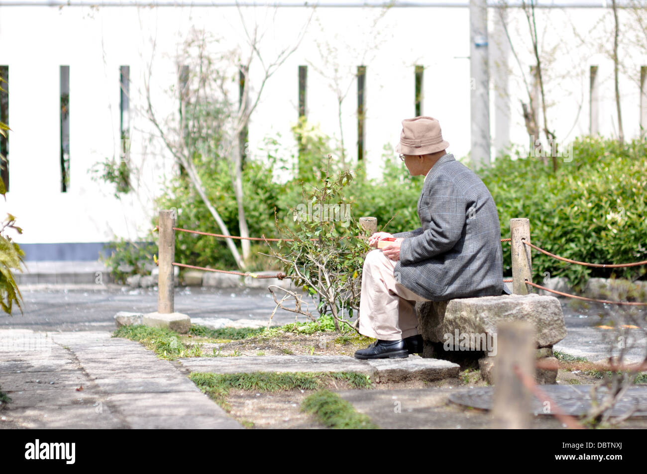 An elderly man sitting alone in a park in Japan. Stock Photo