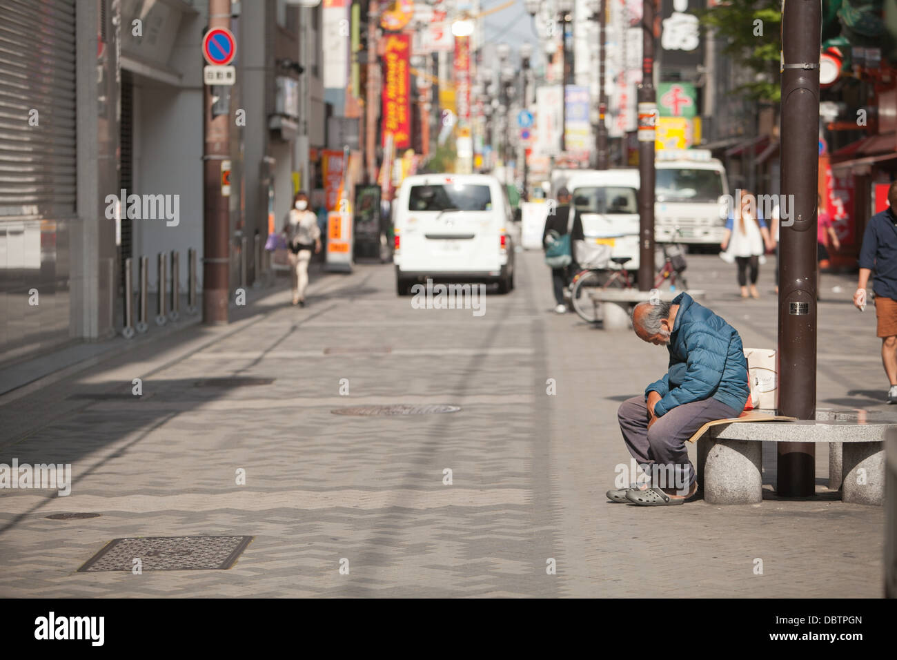 Street detail in Osaka, Japan - a homeless man on a Saturday morning Stock Photo