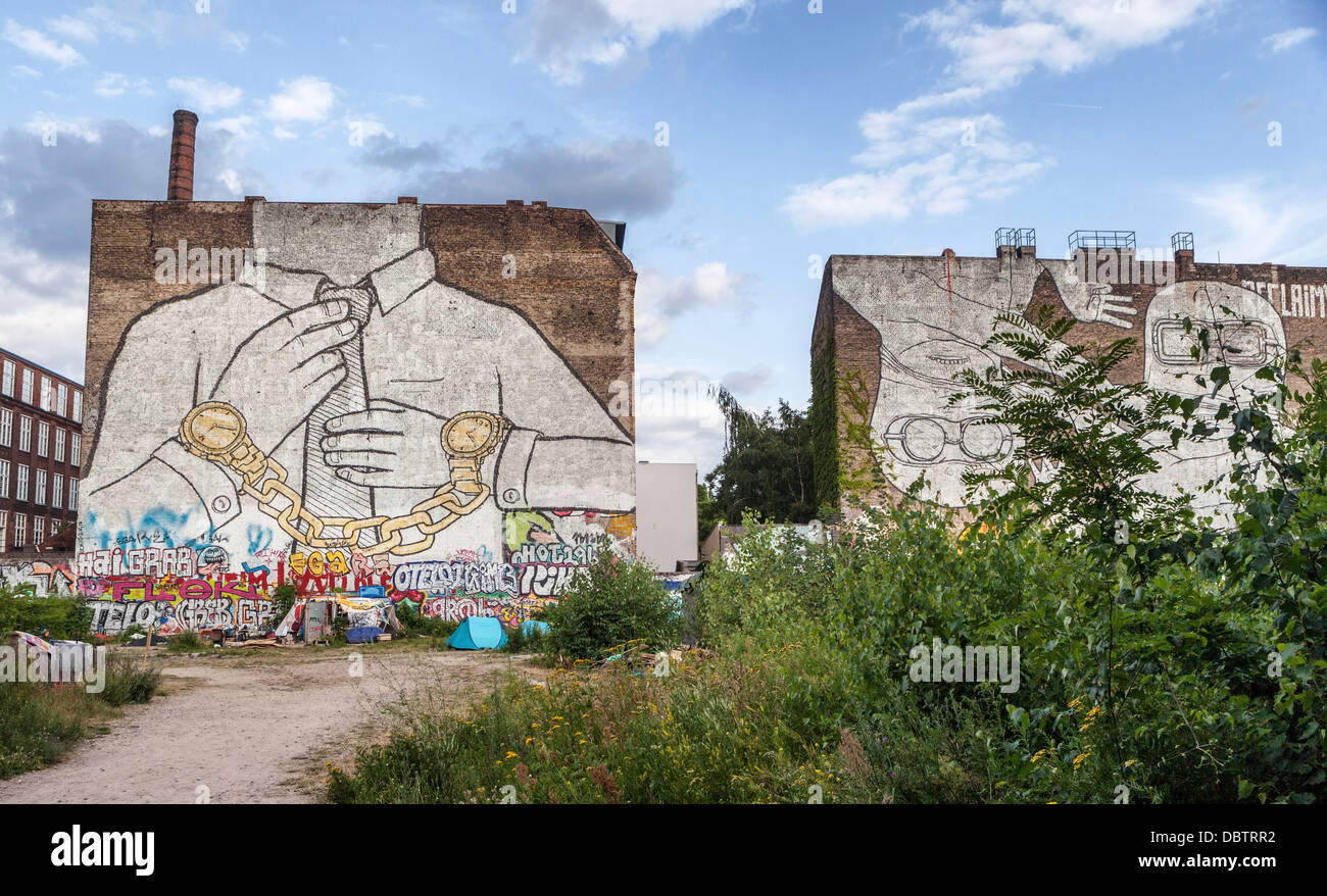 Two giant white murals by street artist Blu - hand-cuffed, headless man and two masked men - Cuvrystrasse, Kreuzberg, Berlin Stock Photo