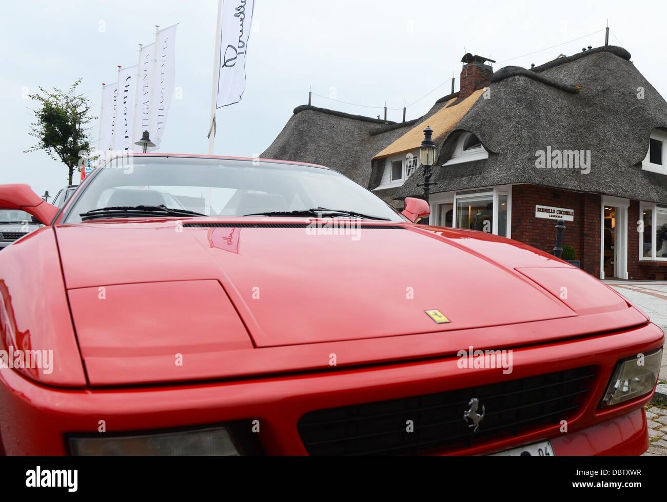 A red Ferrari stand in front of a thatched house in Kampen on the island of Sylt, Germany, 26 July 2013. Photo: Jens Kalaene Stock Photo