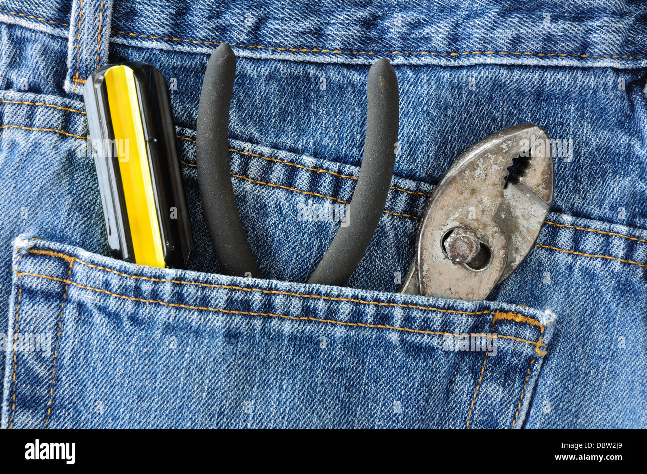 Hand tools in a back pocket of a pair of denim jeans Stock Photo