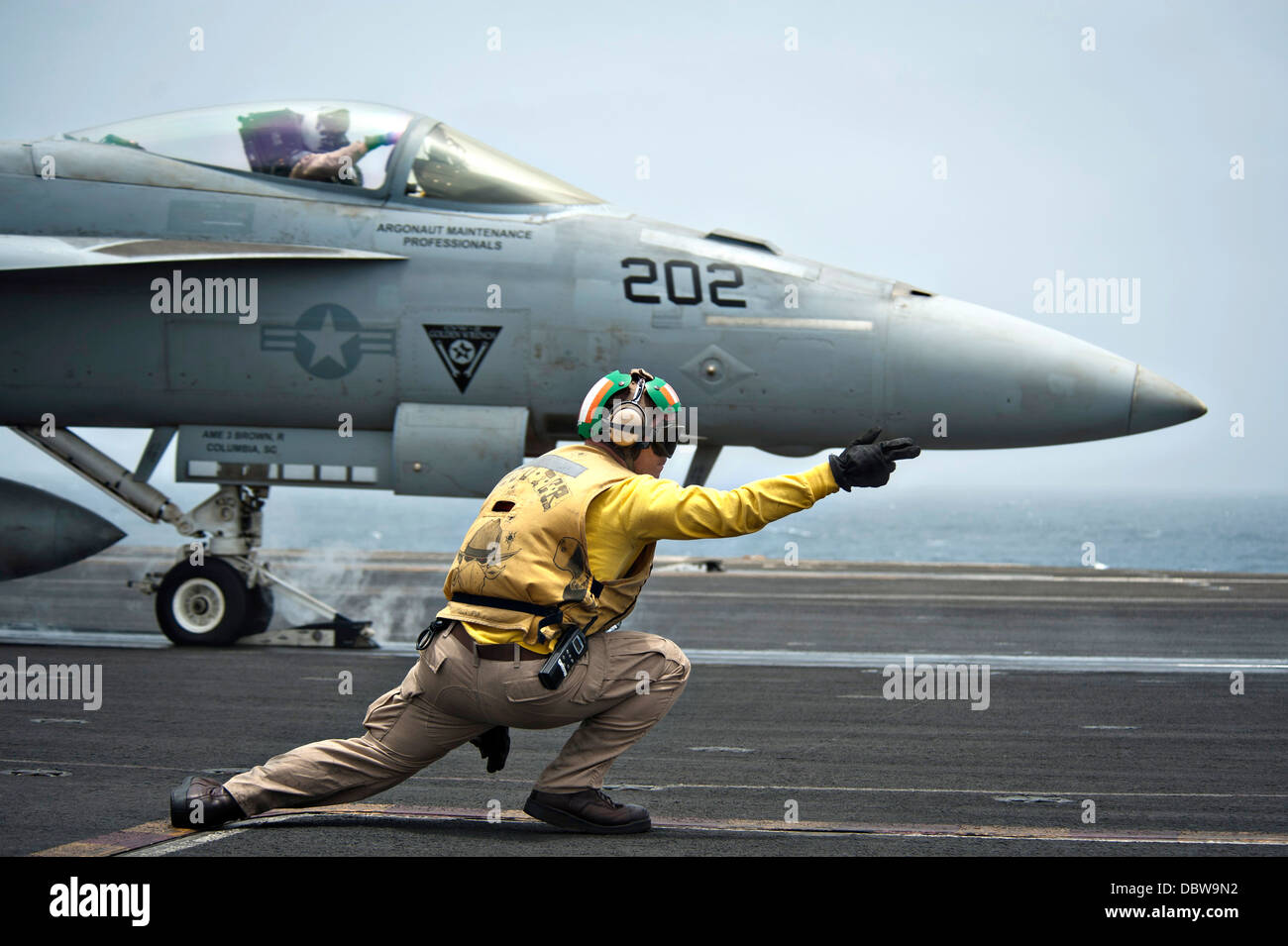 a-us-navy-aviation-boatswain-mate-signals-a-fa-18e-super-hornet-fighter-DBW9N2.jpg