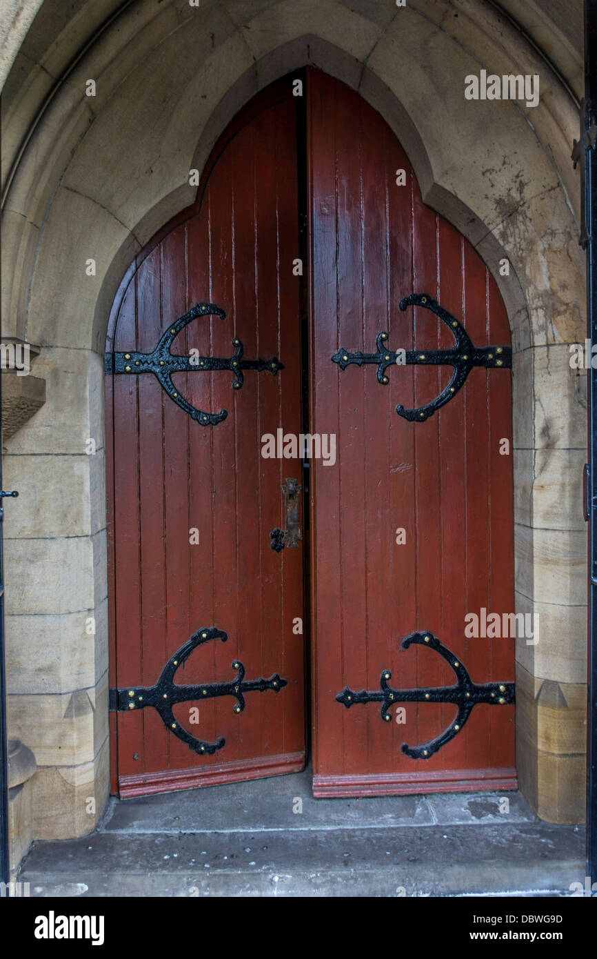 Slightly open wooden church door with iron work on door stone entrance Stock Photo