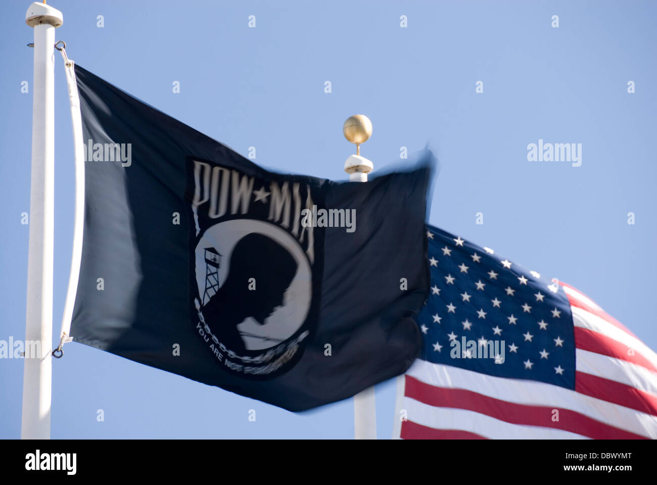 Close up on black pow mia flag and stars and stripes American flag flying together, USA Stock Photo